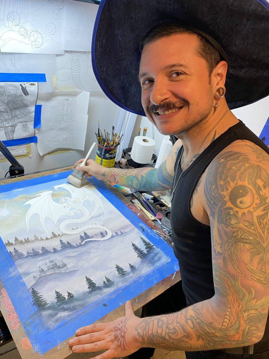 Michael Lombardi, wearing a wizard hat, painting a white dragon in his studio